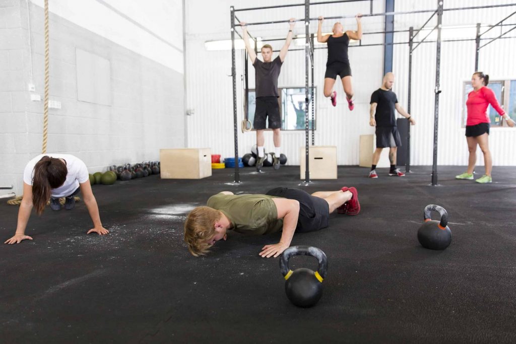 Workout group does exercises at fitness gym Training push ups, hang ups and squat at a fitness gym center. Group workout.
